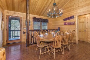 L’intérieur est en bois et comprend une table à manger dressée pour six personnes, entourée de chaises en bois. Un lustre est suspendu au plafond, et une pancarte sur le mur indique qu’il y a des frais de 5 dollars pour les plaintes.