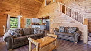 L’intérieur d’une cabane en bois comprenant un salon, une cuisine et un escalier.