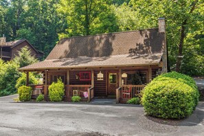 A rustic log cabin-style building with a porch, a chimney, and a sign indicating it is a restaurant.