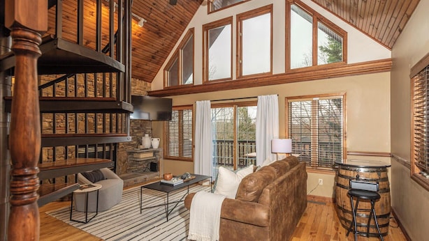 A spacious loft-style living area with high ceilings, large windows, a fireplace, and a cozy seating arrangement.