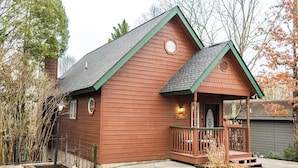 A wooden cabin with a porch, a small deck, and a mailbox.