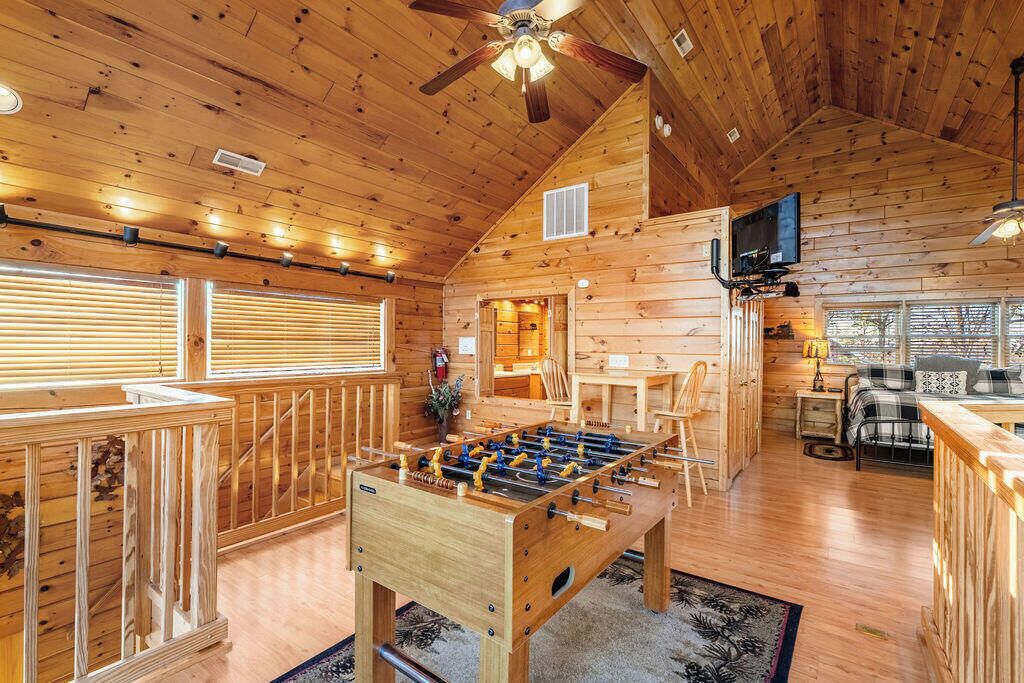 Un intérieur chaleureux de chalet en bois, avec un baby-foot, un coin bar et un espace repas.