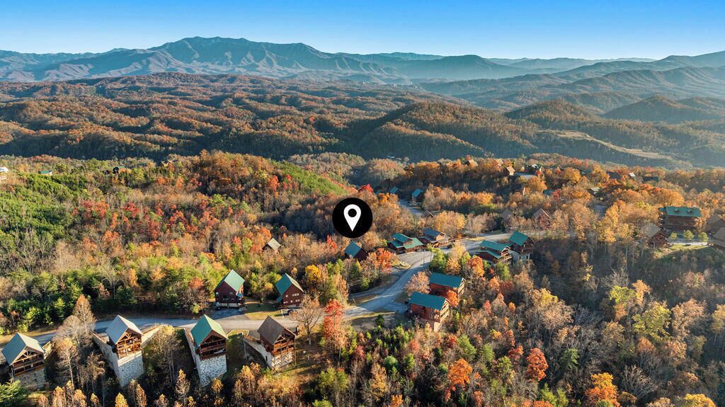 A lodge with multiple cabins surrounded by autumn foliage and mountains in the background.