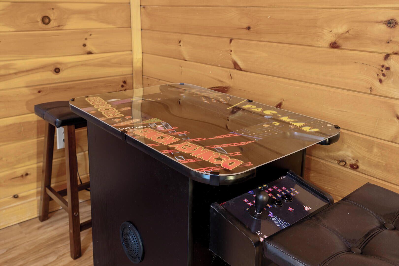A wooden table with a glass top, a joystick controller, and a speaker.