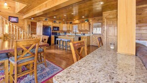 A wooden cabin interior with a kitchen, dining area, and a staircase. - Heavenly Hideaway (Sevierville)