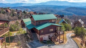A two-story log cabin with a green roof, a porch, and a staircase leading to a deck. - Heavenly Hideaway (Sevierville)
