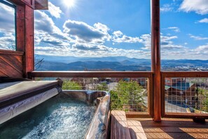 A hot tub with a wooden deck and a view of mountains and a town. - Heavenly Hideaway (Sevierville)
