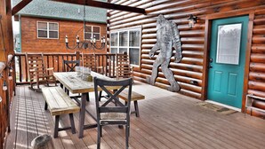 A wooden cabin with a dining area featuring a wooden table and chairs, a hanging light fixture, and a turquoise door.