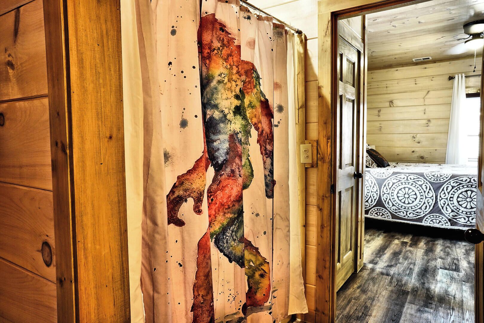 A wooden interior with a large abstract painting on a wall, a bed with patterned bedding, and a wooden floor.