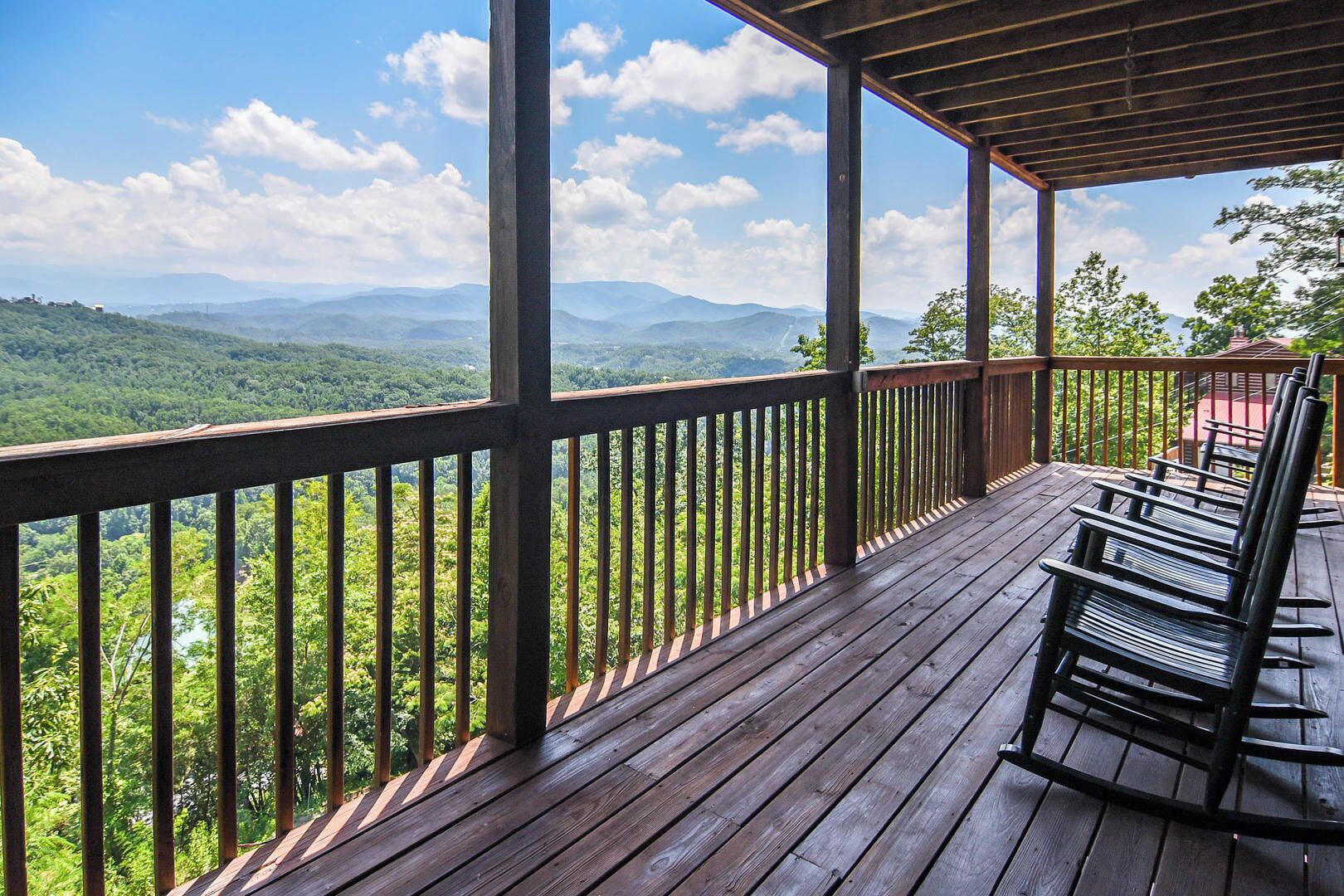 A wooden deck with a railing overlooking a mountainous landscape.