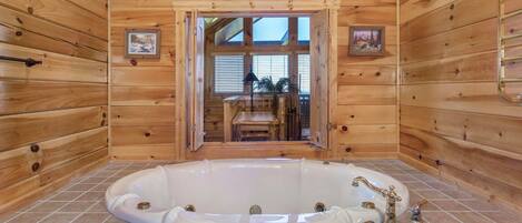 A wooden cabin with a large bathtub, wooden walls, and a view through a door.