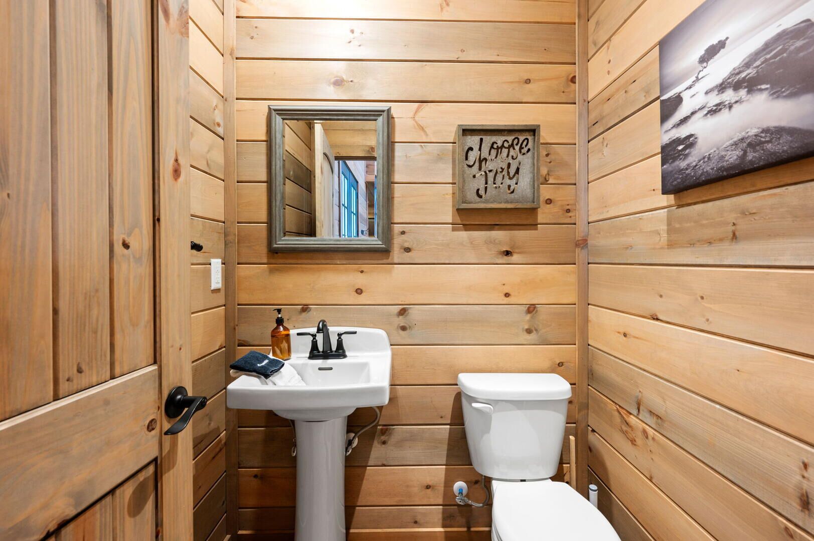 Ein Badezimmer mit Holzvertäfelung, einem Waschbecken, einer Toilette und einem Spiegel.