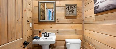 Ein Badezimmer mit Holzvertäfelung, einem Waschbecken, einer Toilette und einem Spiegel.