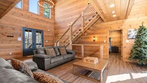 A spacious wooden cabin with a large living area, a staircase, and a cozy fireplace. - The Phoenix (Sevierville)