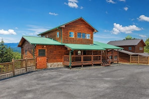 A two-story wooden lodge with a green roof, a covered porch, and a stone foundation. - Starr Crest Lodge (Sevierville)