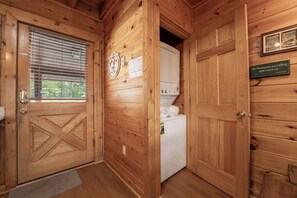 A wooden interior with a door, a window with blinds, a wall-mounted clock, and a sign with a quote. - Starr Crest Lodge (Sevierville)