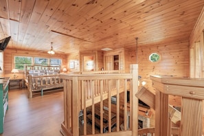 L’intérieur d’une cabane en bois comprend une chambre à coucher située en mezzanine, un coin repas et une cheminée.
