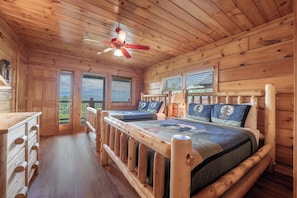 A cabin interior with a wooden bed, a dresser, and a ceiling fan. - Starr Crest Lodge (Sevierville)