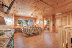 A wooden cabin interior with a bed, a dining table, and a ceiling fan. - Starr Crest Lodge (Sevierville)