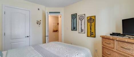 Un dormitorio con cama, ventilador de techo, cómoda y decoración en la pared.