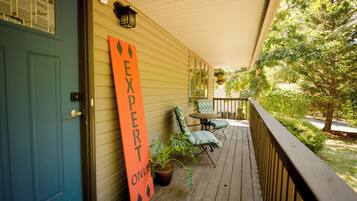 A porch with a blue door, a sign that reads "EXPERT ONLY", two chairs, and a potted plant.
