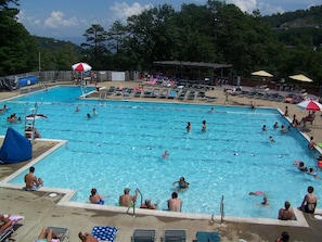 Ein Schwimmbecken mit mehreren Bahnen, Liegestühlen und Sonnenschirmen.