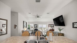 A modern kitchen with a granite countertop, stainless steel sink, and a ceiling fan. - Stylish Golfside Getaway (Wildwood)