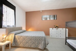 A bedroom with a bed, bedside table, dresser, and a painting on the wall.
