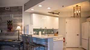 A kitchen with white cabinets, a bar area, and a door. - Most complete resort like in New Smyrna Beach (New Smyrna Beach)