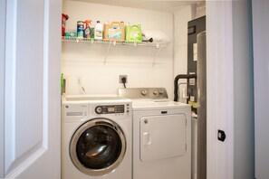 A laundry closet equipped with a washer, dryer, and overhead storage shelf.
