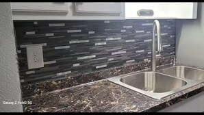 A kitchen with a double sink, a stainless steel faucet, and a backsplash with a geometric pattern. - Private getaway by the beach (Pensacola)
