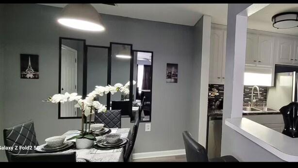 A modern dining area with a Galaxy Z Fold2 50L table, white walls, and a kitchen with white cabinets and stainless steel appliances. - Private getaway by the beach (Pensacola)