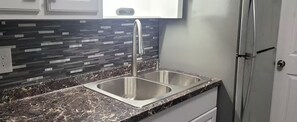A kitchen with a double sink, a stainless steel faucet, and a backsplash with a geometric pattern. - Private getaway by the beach (Pensacola)