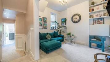 A living room with a teal sofa, a round coffee table, and a bookshelf.