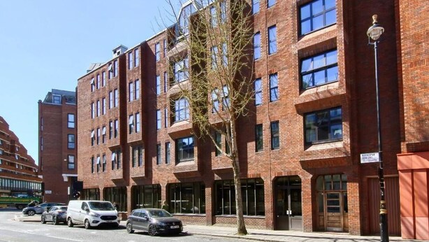 A multi-story brick building with large windows and a tree in front. - Elegant 1BR Flat in Westminster Near Victoria Tube (London)