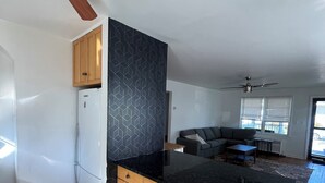 Une cuisine moderne avec des armoires en bois, un plan de travail noir et un ventilateur de plafond.
