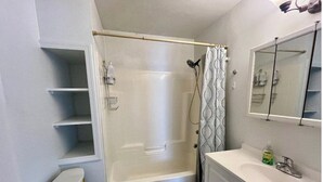 Une salle de bain comprenant des toilettes, une douche, un lavabo et un miroir.
