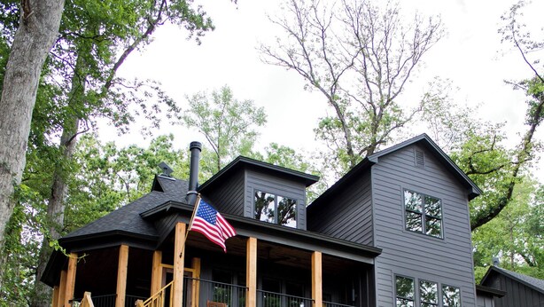 A two-story wooden house with a balcony and a staircase leading to the upper level.