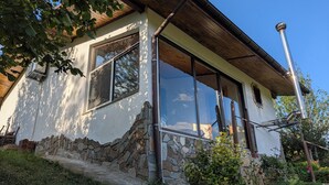 Ein Haus mit steinernen Fundament, großen Fenstern und einem Holzdach.