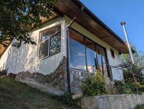 Ein Haus mit steinernen Fundament, großen Fenstern und einem Holzdach.