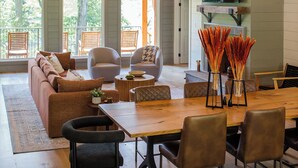 Un salon spacieux avec un plafond haut, des poutres apparentes, une grande table à manger et des sièges confortables.