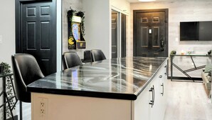 Una cocina moderna con encimera de mármol, sillas negras y una mesa de comedor.