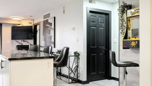 Una cocina moderna con encimera de mármol, taburetes negros y una puerta negra.