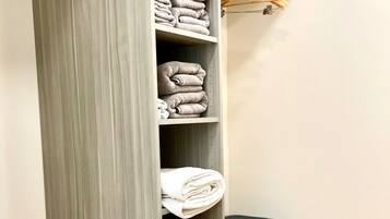 Een inloopkast met meerdere planken voor opgevouwen kleding, een kledingroede en een prullenbak.