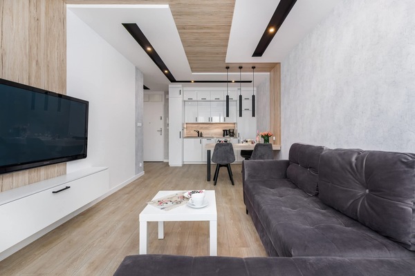 An open living space with a mounted TV and corner sofa facing the dining table.