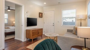Un salon avec un canapé, une table basse, un téléviseur et une porte.