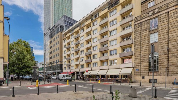 A multi-story hotel with a modern facade, a prominent Samsung sign, and a street view with a crosswalk and bollards.
