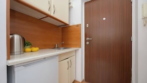 A compact kitchen with a sink, a kettle, and lemons on the counter.
