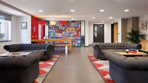 A modern lounge area with two grey sofas, a wooden table, and a colorful wall mural. - For Students Only - Modern Accommodation in Leeds City Centre (Leeds)