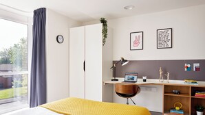 A bedroom with a bed, a desk, a laptop, a bookshelf, and a window with curtains. - For Students Only - Modern Accommodation in Leeds City Centre (Leeds)
